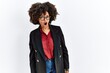 © Krakenimages.com - African american woman with afro hair wearing business jacket and glasses in shock face, looking skeptical and sarcastic, surprised with open mouth