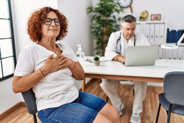 Poster - Senior woman sitting at doctor appointment smiling with hands on chest with closed eyes and grateful gesture on face. health concept.