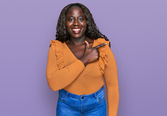 Poster - Young african woman wearing casual clothes cheerful with a smile of face pointing with hand and finger up to the side with happy and natural expression on face