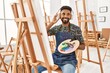 © Krakenimages.com - Young african american artist man smiling happy listening to music and painting at art studio.