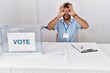 © Krakenimages.com - Young handsome man at political election sitting by ballot doing ok gesture like binoculars sticking tongue out, eyes looking through fingers. crazy expression.