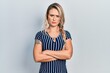 © Krakenimages.com - Beautiful young blonde woman wearing casual striped dress skeptic and nervous, disapproving expression on face with crossed arms. negative person.