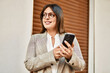 © Krakenimages.com - Young hispanic businesswoman smiling happy using smartphone at the city.