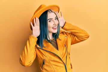 Wall Mural - Young modern girl wearing yellow hat and leather jacket smiling cheerful playing peek a boo with hands showing face. surprised and exited