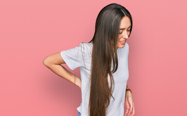 Poster - Young hispanic girl wearing casual white t shirt suffering of backache, touching back with hand, muscular pain