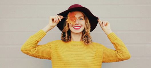 autumn portrait of beautiful happy smiling young woman covering her eyes with yellow maple leaves we