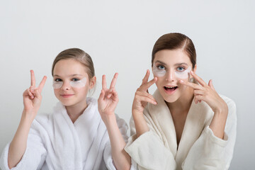 Two girls playing with cosmetic SPA mask and eye panda patches mask on their faces. Little girl and young woman enjoy home spa treatments. SPA and wellness concept