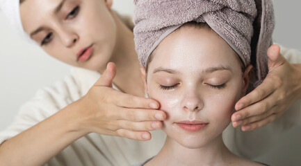 Poster - Little girl enjoys mask and massage on her faces. Two girls playing with cosmetic SPA mask on their faces. Little girl and young woman enjoy spa treatments. SPA and wellness