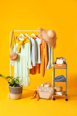 Sticker - Rack with stylish clothes, shoes and accessories on color background