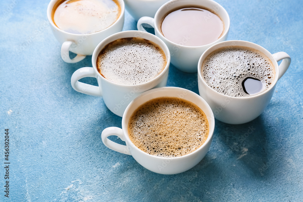 Cups of tasty coffee on color background