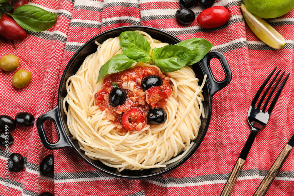 Frying pan with tasty Pasta Puttanesca on table