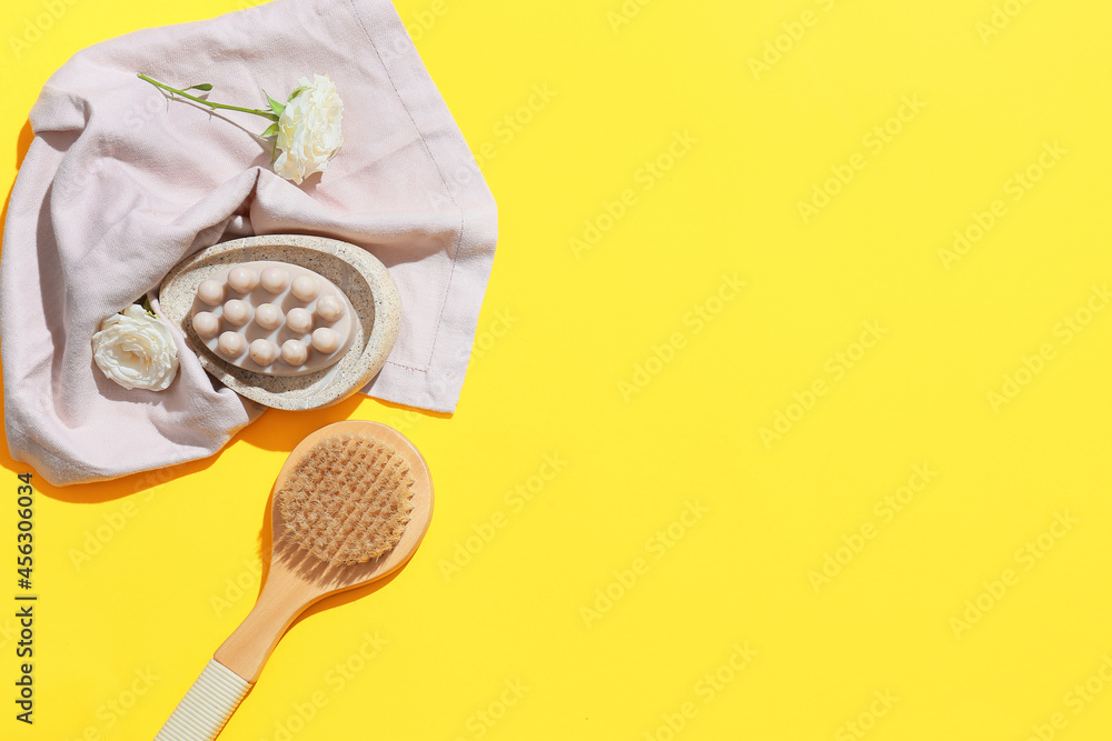 Composition with massage soap bar, brush and flowers on color background