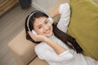© Chanakon - Relaxing time on sofa. Beautiful young asian woman lay down on sofa and listening to the music with headphone. She has rhythm Lifestyle in living room at house in the morning.