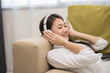 © Chanakon - Relaxing time on sofa. Beautiful young asian woman lay down on sofa and listening to the music with headphone. She has rhythm Lifestyle in living room at house in the morning.