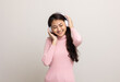 © Chanakon - Cheerful asian female teenager listen to the music with white headphone on isolated. Beautiful young woman in pink shirt hand touch a wireless headphone having fun with the music in  room.