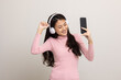 © Chanakon - Beautiful young asian women choose song and play music from smartphone connection with wireless headphone having fun in home. Teenage girl listen to the music enjoy relaxing on isolated background.