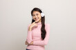 © Chanakon - Cheerful asian female teenager listen to the music with white headphone on isolated. Beautiful young woman in pink shirt hand touch a wireless headphone having fun with the music in  room.