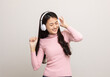 © Chanakon - Cheerful asian female teenager listen to the music with white headphone on isolated. Beautiful young woman in pink shirt hand touch a wireless headphone having fun with the music in  room.