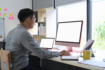 Side view businessman working with multiple gadgets in modern office.