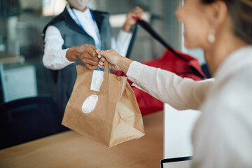 Close-up of businesswoman receives food delivery while working in the office.