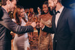 © gstockstudio - Group of people in formalwear toasting with champagne and smiling while spending time on luxury party
