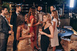 Group of beautiful young people in formalwear communicating and smiling while spending time on luxury party