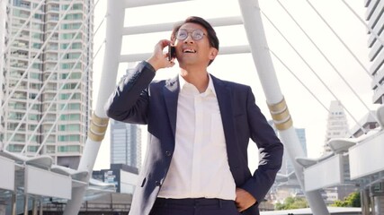 Wall Mural - Asian confidently business man in glasses and suit talking on mobile phone outdoor in city.