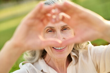 Happy woman looking through heart sign