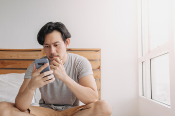 Asian man looking at smartphone with serious face.