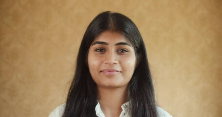 Poster - A south asian girl wearing a white shirt standing in front of a beige background doing things in HD