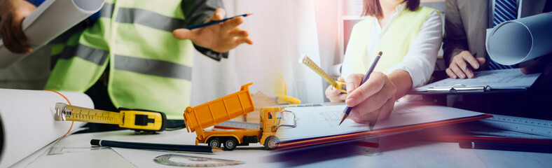 Close up of civil male engineer asian working on blueprint architectural project at construction site at desk in office.