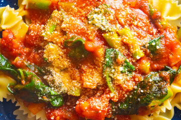 a culinary dish made with spinach, tomatoes, chicken,   asparagus pieces and sprinkles of parmesan cheese piled up on a plate for a tasty lunch.