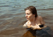 © YAROSLOVEPHOTOVIDEO - Young wet woman looks into the distance in the water on the river. Swimming and relaxation. Nature background