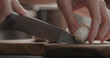 man cutting mozzarella balls on olive wood board