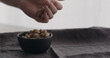 man hand take salted pistachios from black bowl on linen cloth