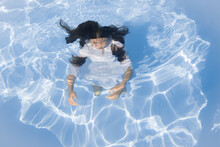 Conceptual Portrait Of Woman In White Dress Underwater In Swimming Pool