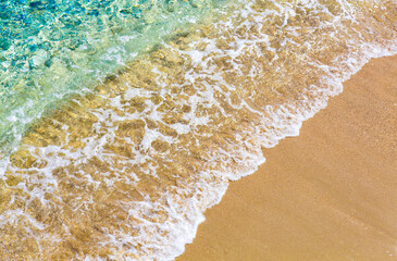 Top view of sandy beach and turquoise ocean water with small waves, beautiful summer sea background. Tropical resort. Copy space.