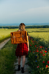 Sticker - Young woman with suitcase on countryside road in summer time