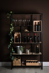 Wall Mural - Rack with bottles of wine and glasses near brown wall