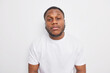 © WHstudio Leushin N - Portrait of handsome dark skinned man looks attentively at camera has self confident expression dressed casually poses against white background. Afro American guy receives task listens instructions