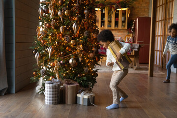 Wall Mural - Overjoyed small teen African American kids have fun unpack open boxes or New Year winter holidays at home. Happy little biracial children unbox packages parcels for Christmas. Celebration concept.