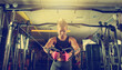 © splitov27 - Slim Fit blonde woman flexing muscles on gym machine. Girl execute exercise with exercise-machine Cable Crossover in dark gym.