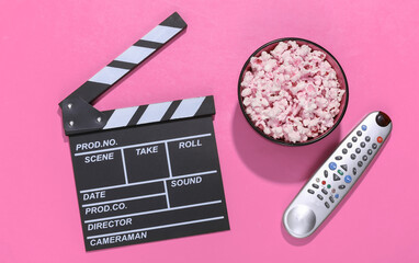 Wall Mural - Movie clapper board, popcorn bowl, tv remote on pink background with deep shadows. Entertainment industry. Top view