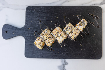 Sticker - Top view of fresh sushi rolls with sesame seeds on a black board