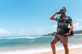 Fototapeta Fototapety z morzem do Twojej sypialni - Cyfrowy nomada, mężczyzna pracujący na tropikalnej plaży z laptopem i telefonem.