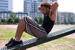 © Image Source Limited - Young man doing sit-ups at outdoor gym