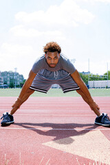 Young man stretching on running track