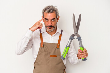 Middle age gardener man holding a scissors isolated on white background  pointing temple with finger, thinking, focused on a task.