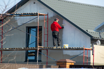 close up details of painting walls, industrial worker using roller and other tools for painting walls of new house