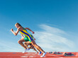 Three female athletes on athletics track, racing